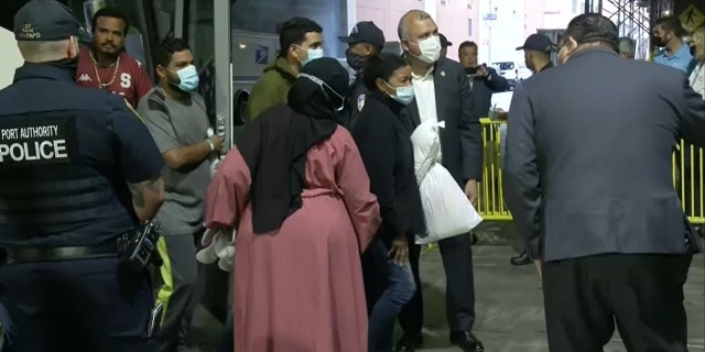 NYC officials help a woman seen limping while getting off a bus from Texas at Port Authority on Aug. 15, 2022.