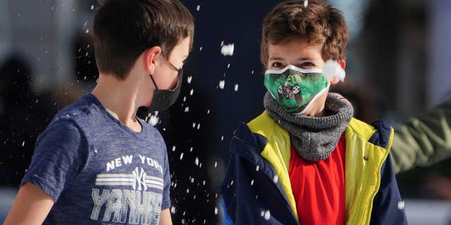 Two young children wear masks while playing in the snow in Bryant Park during the COVID pandemic in the New York City borough of Manhattan, New York, the United States, on January 14, 2022.