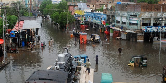 Люди в Пакистане изо всех сил пытаются пробраться через затопленные улицы после муссонных дождей, вызвавших внезапные наводнения в Хайдарабаде, Пакистан, в среду, 24 августа 2022 года.