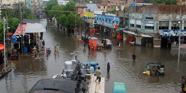 Menschen in Pakistan kämpfen darum, sich durch überflutete Straßen zu bewegen, nachdem Monsunregen am Mittwoch, den 24. August 2022, Sturzfluten in Hyderabad, Pakistan, ausgelöst haben.