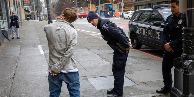 Police officers check on a man who said he has been smoking fentanyl in downtown Seattle on March 14, 2022.
