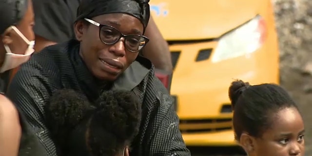 Kutin Gyimah's widow, Abby Gyimah, embraces her children.