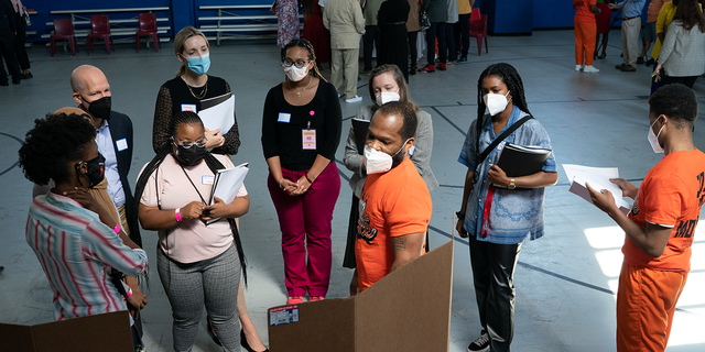 Charles Jenkins, 42, center, and his teammate, DeMarco Harris, 19, right, present their plan to a group of listeners. Students in the LEAD Up! Program at the Washington, D.C., DOC have been challenged to come up with solutions to reduce gun violence in the District. A "think science fair" was held on Wednesday, August 3, 2022 for the teams to present their ideas to an audience.