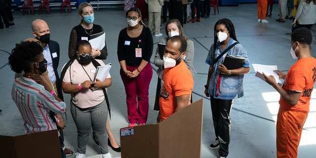 Charles Jenkins, 42, center, and his teammate, DeMarco Harris, 19, right, present their plan to a group of listeners. Students in the LEAD Up! Program at the Washington, D.C., DOC have been challenged to come up with solutions to reduce gun violence in the District. A "think science fair" was held on Wednesday, August 3, 2022 for the teams to present their ideas to an audience.