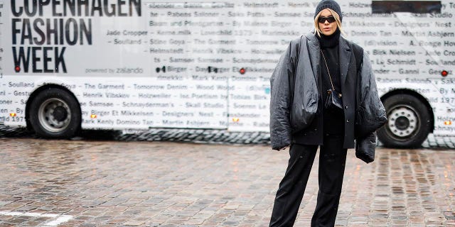 Influencer Gigi Vives wearing a black jacket by Yeezy x Gap, a black blazer by Mango, a black hoodie by Weekday, black pants by na-kd, black boots by H&M and a black bag with gold details by Fendi, seen at the GESTUZ fashion show on February 1, 2022 in Copenhagen, Denmark.