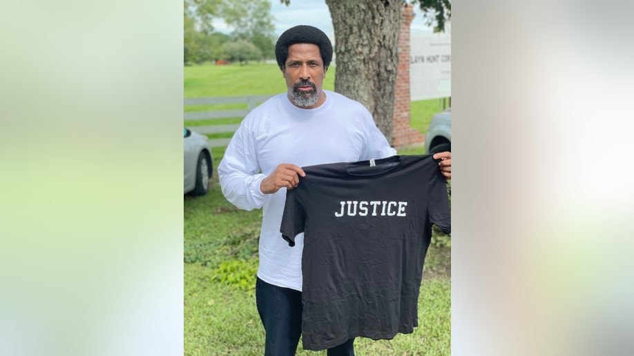 Sullivan Walter holds up a t-shirt that says, 'Justice'