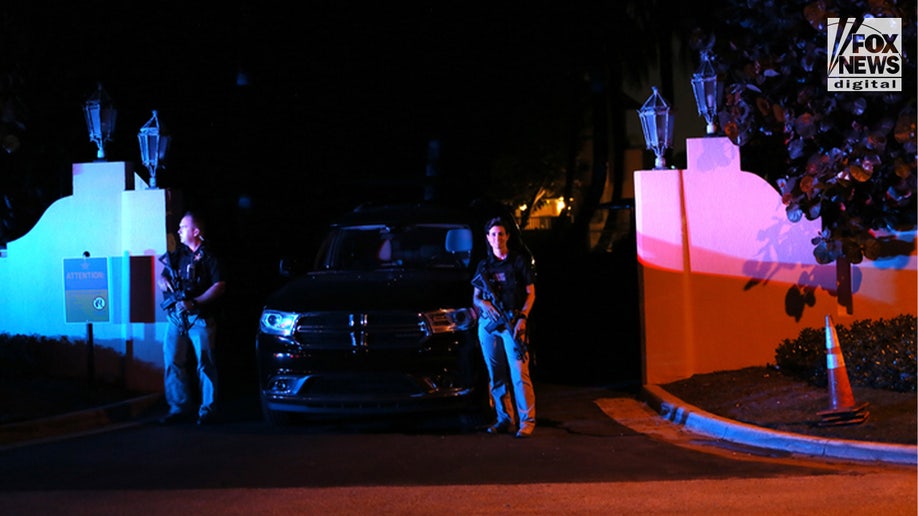 A guard with a gun stands outside Mar-a-Lago near a black truck