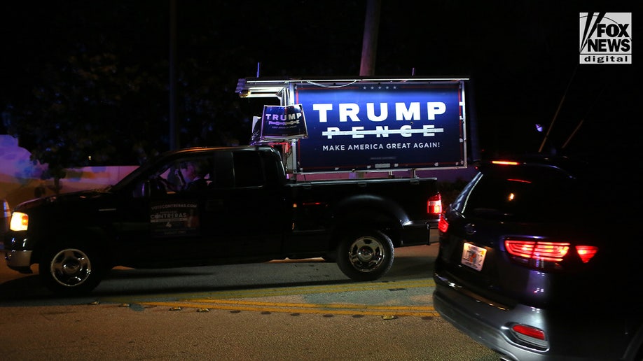 A truck with a Trump sign in the bed is driven by Mar-a-Lago