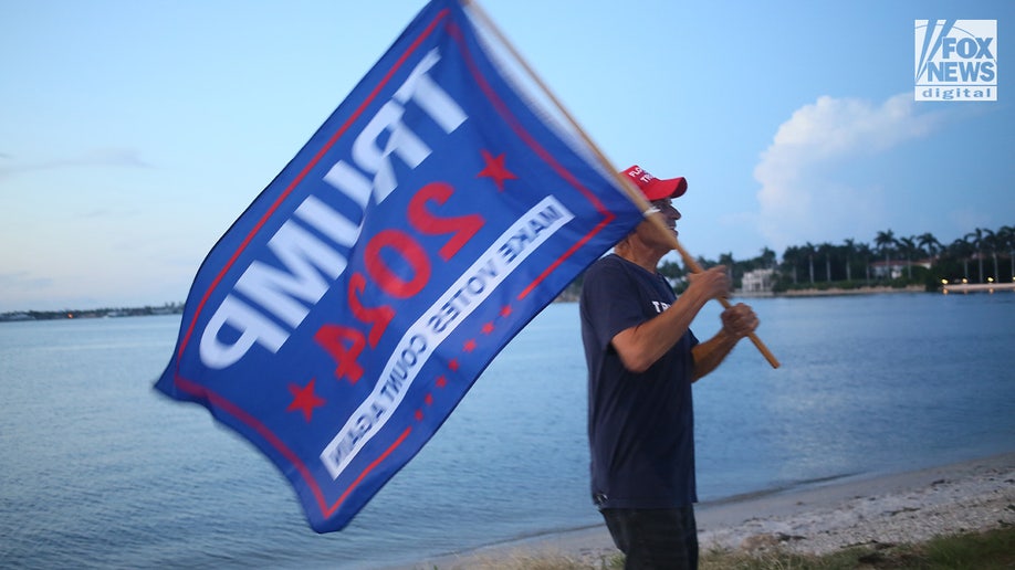 Man with a Trump 2024 flag outside Trump's Florida home