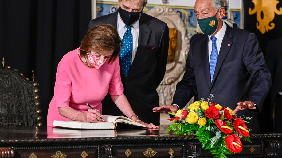 The Speaker of the United States House of Representatives Nancy Pelosi (L) signs the honor book as her husband Paul Pelosi (C) and Portuguese President Marcelo Rebelo de Sousa (R) look on