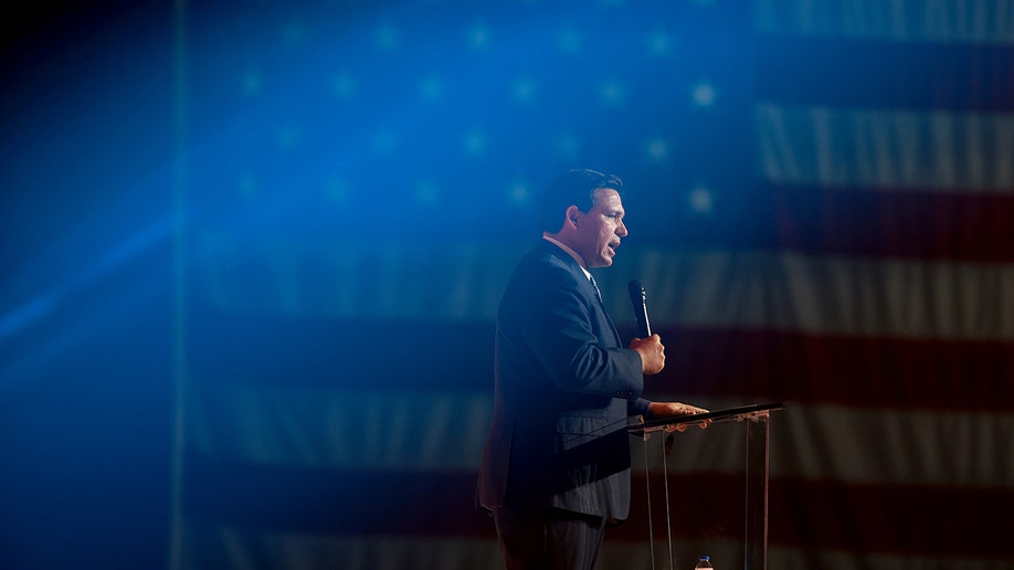 A distant photo of Ron DeSantis in front of an American flag