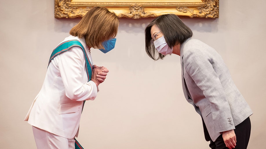 Nancy Pelosi bowing to Taiwan's President Tsai Ing-wen, both in suits