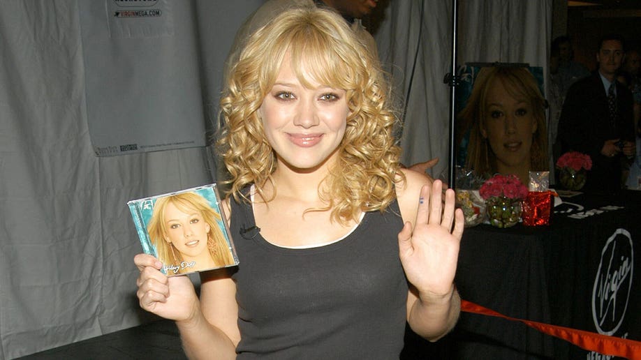 Hilary Duff holding one of her albums