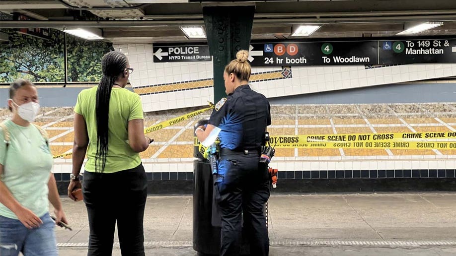 NYC police officer stands next to a subway rider