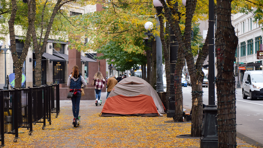 Woman in Seattle walks by tent set up in Seattle, Washington