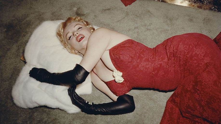 Marilyn Monroe lying down in a red dress.