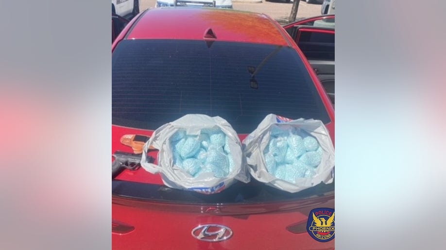 gun and fentanyl pills on the back of a car