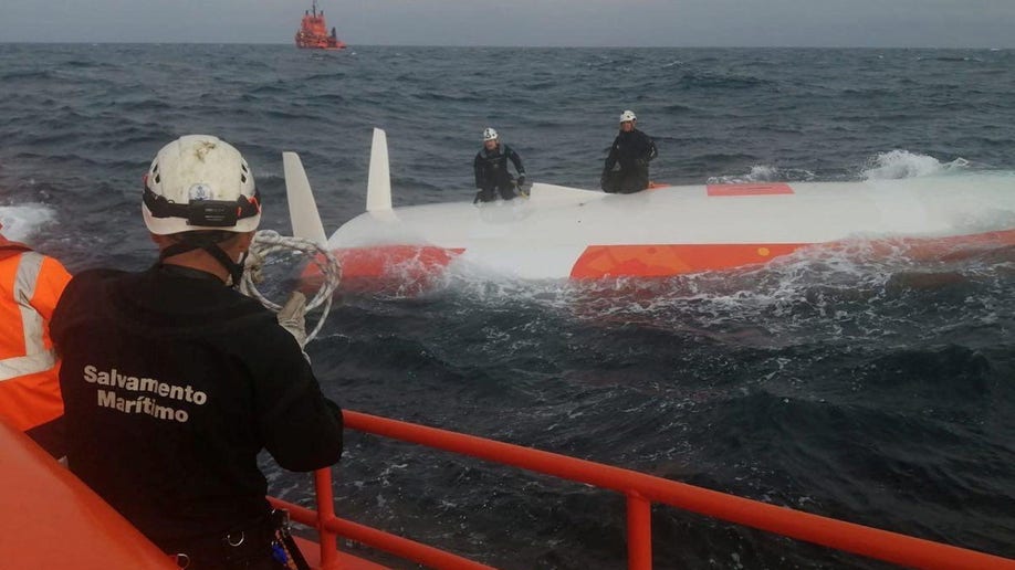 Rescuers on the hull of the capsized boat