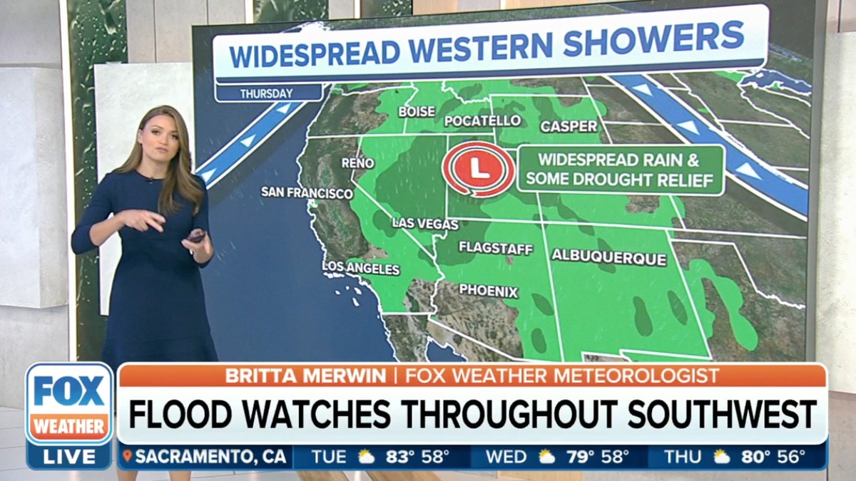 A woman weather reporter stand in front of a map showing rain in the west