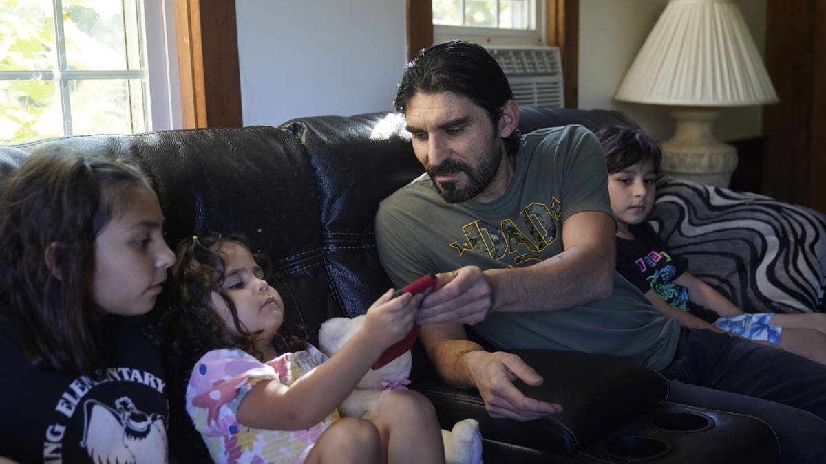 Man on black couch with his children