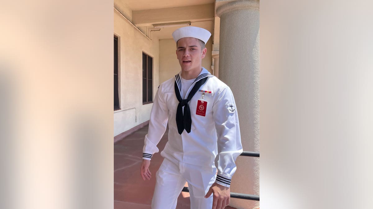 Sailor in uniform standing outside of building in front of a pillar.