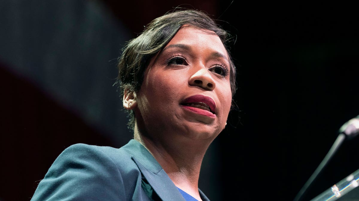 Andrea Campbell at the podium in front of a black background