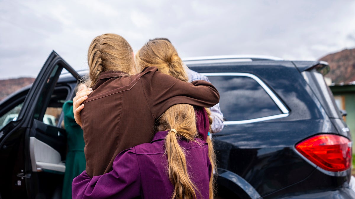 Three girls embrace before they are removed from the home of Samuel Bateman