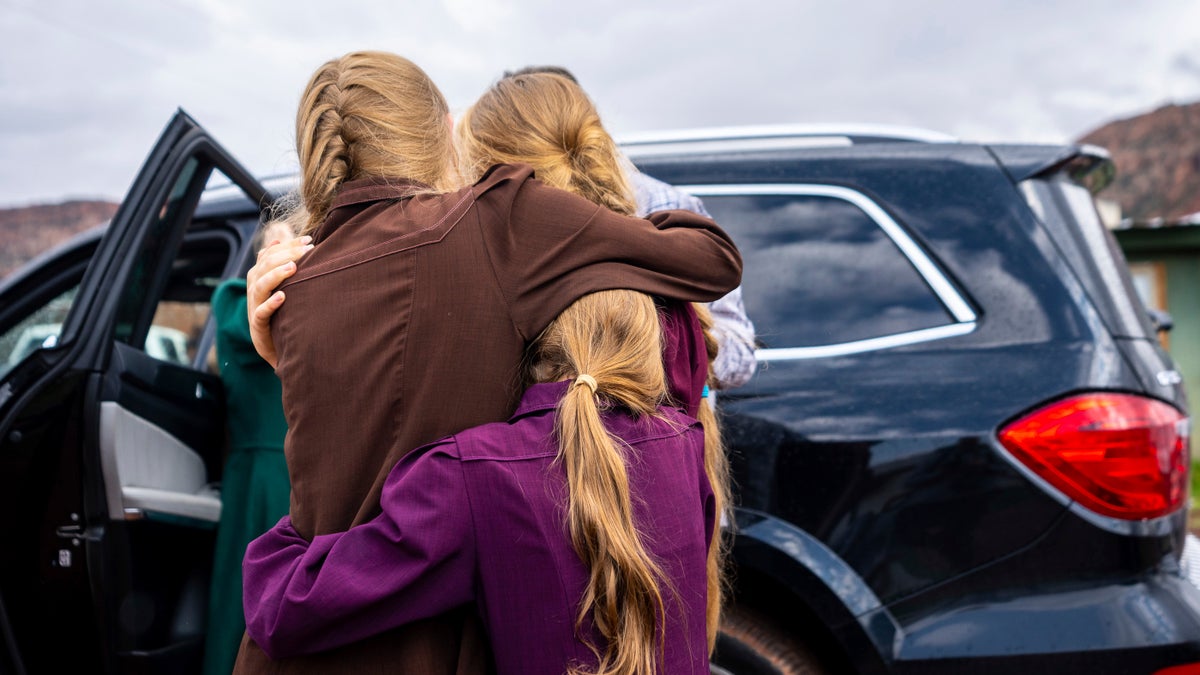 Three girls embrace before they are removed from the home of Samuel Bateman