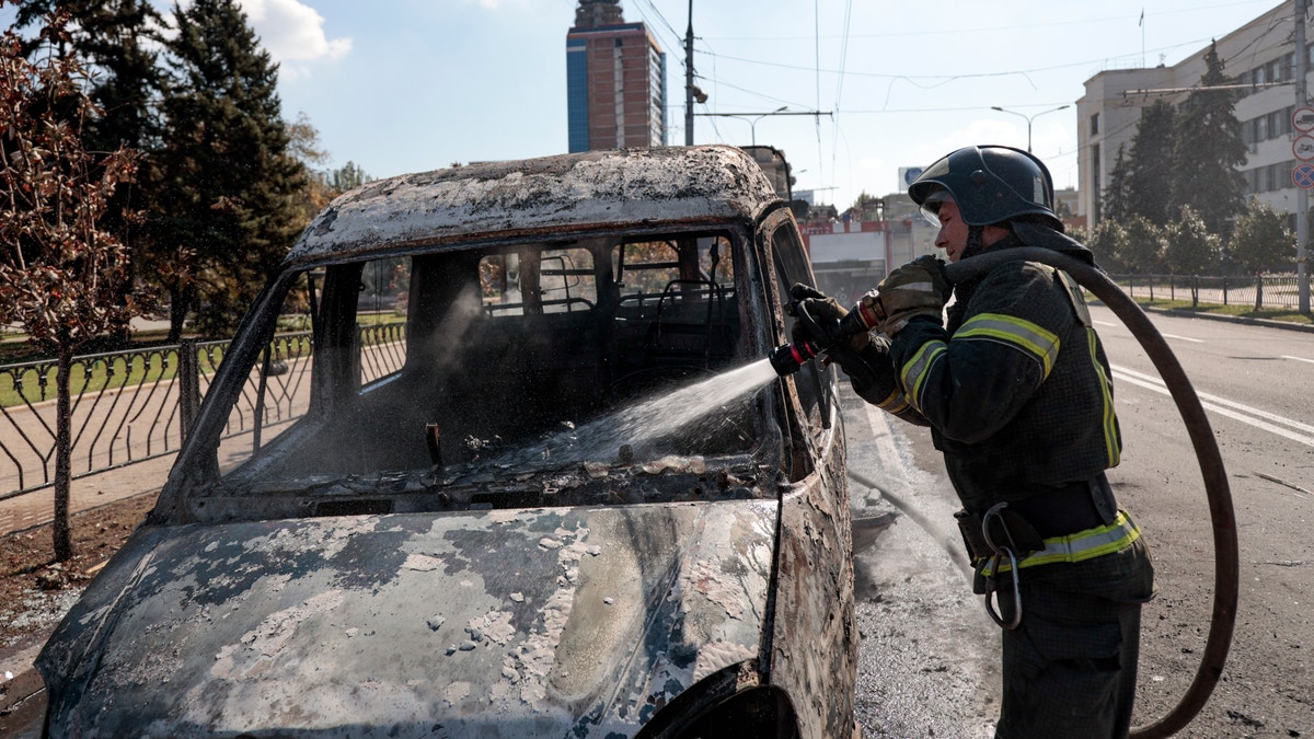A firefighter extinguishes a burning vehicle after shelling in Donetsk