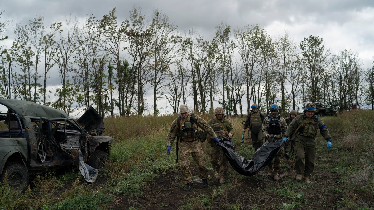 Ukrainian national guard servicemen carry a bag containing the body of a Ukrainian soldier