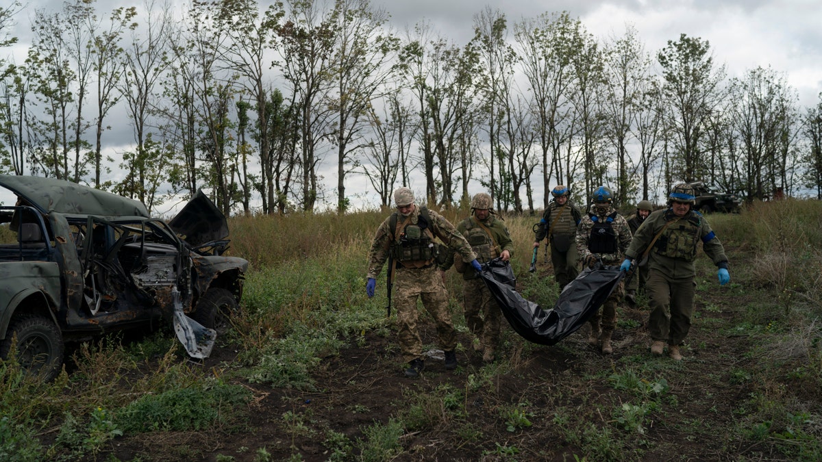 Ukrainian national guard servicemen carry a bag containing the body of a Ukrainian soldier