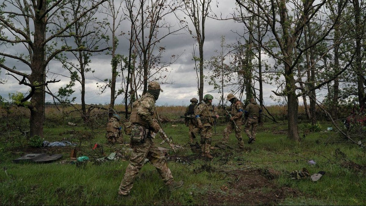 Ukrainian servicemen check the site where a body of a Ukrainian soldier was found inside an armored vehicle