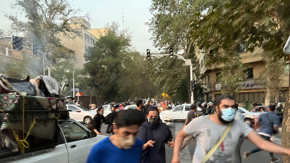 Iranians run from police during a protest