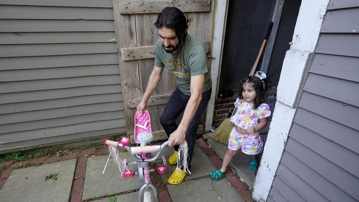 Man with little girl walking out the door with a tricycle