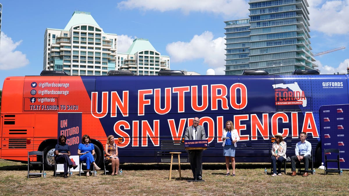 Fred Guttenberg speaking at a podium in front of a campaign bus