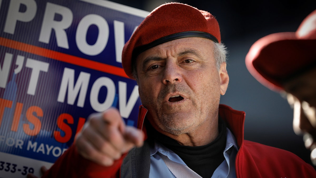 Curtis Sliwa points while wearing his red Guardian Angels hat and jacket
