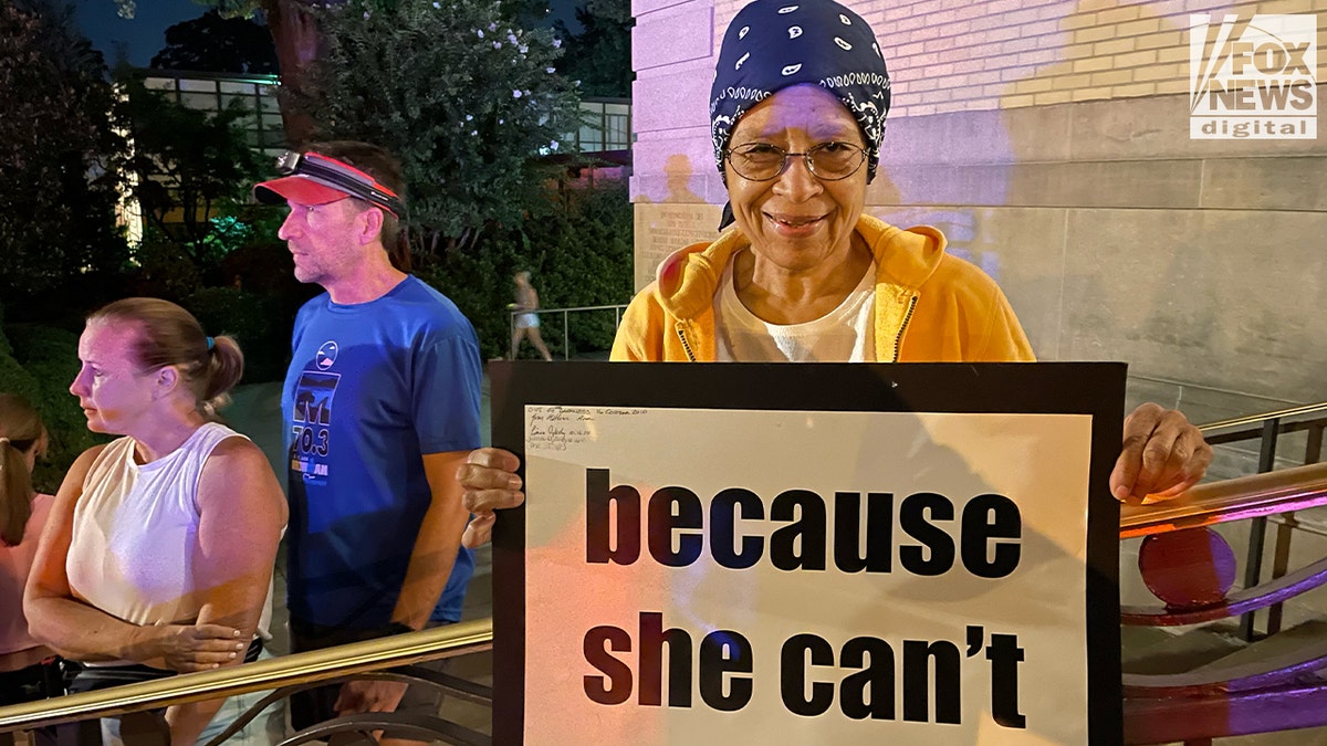 Woman wearing yellow jacket and holding a sign