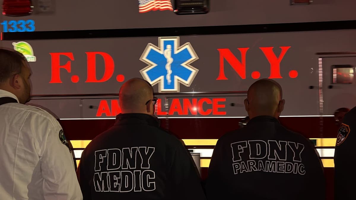 EMS personnel looking at an ambulance carrying a fallen paramedic