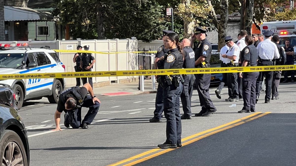 Police standing inside crime scene tape in an intersection