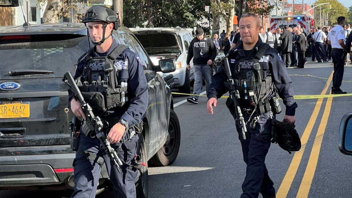 Two policemen carrying big guns move onto a crime scene
