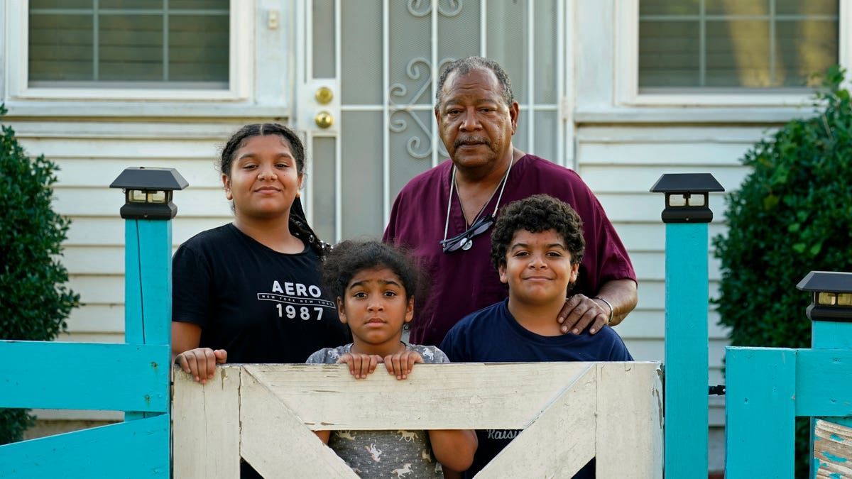Family standing outside home, behind a fence