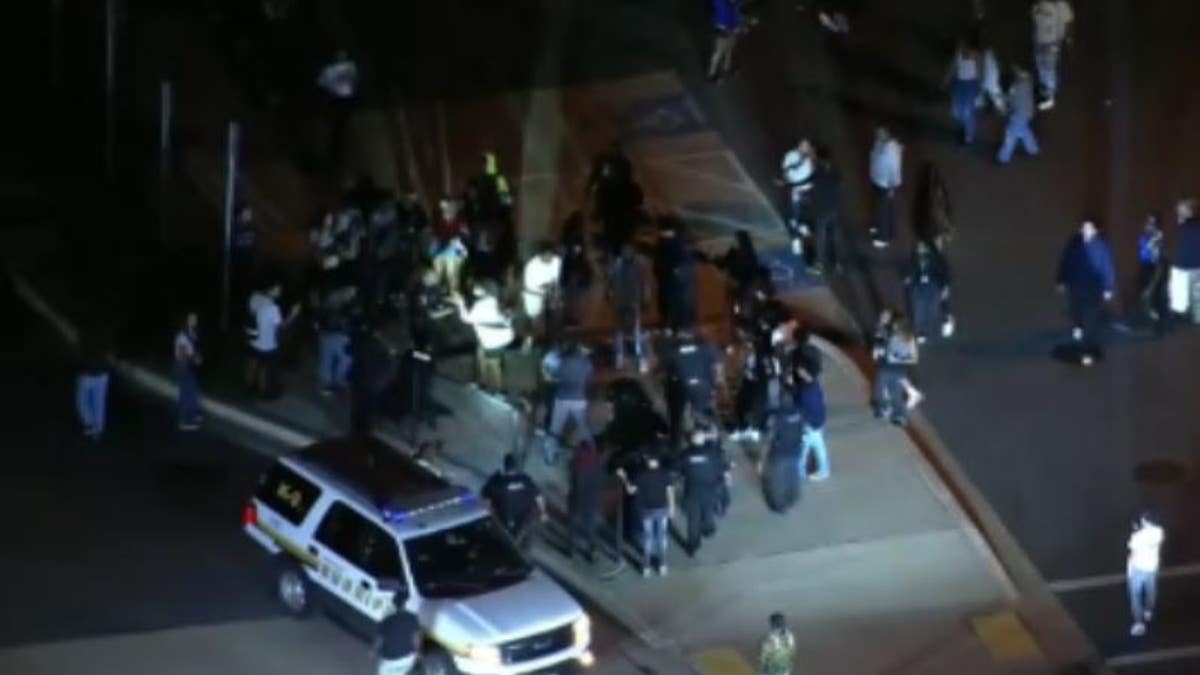 Police shining lights on crowd of people in a parking lot