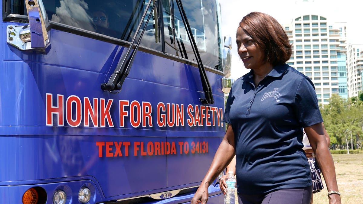 Val Demings walking in front of a campaign bus