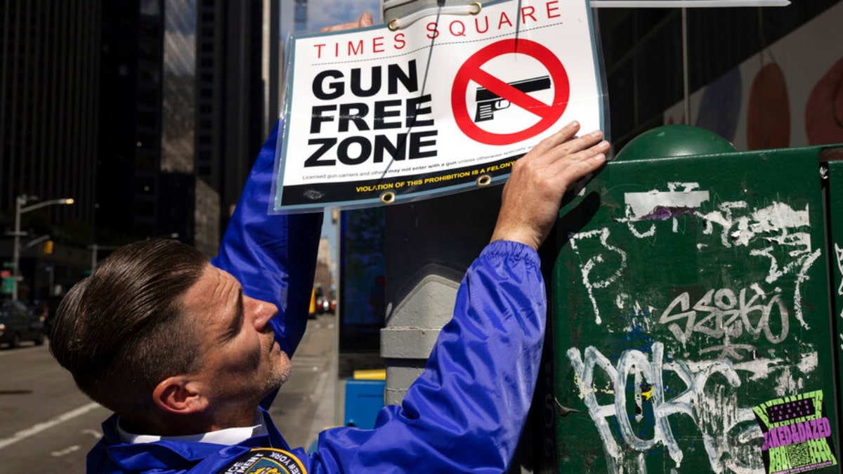 An NYPD officer hands Gun Free Zone signs