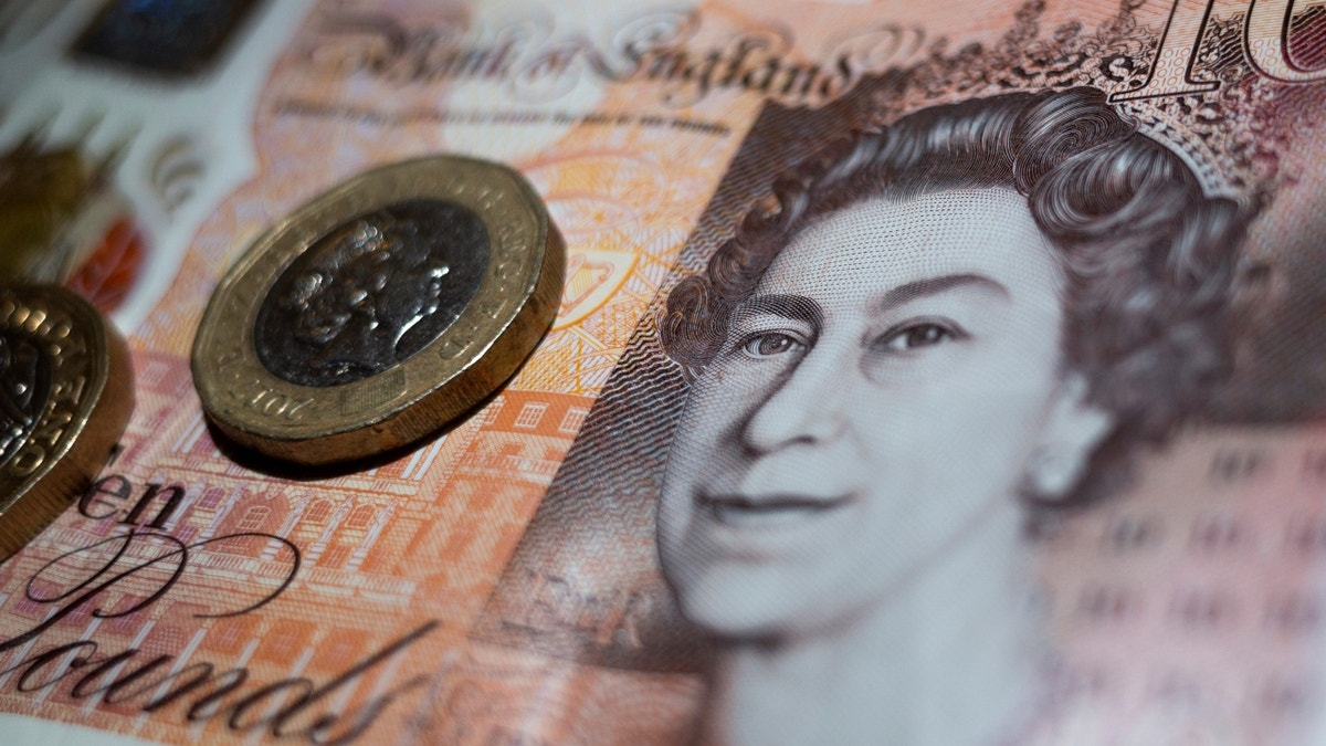 Two one pound coins on a ten pound British note featuring Queen Elizabeth