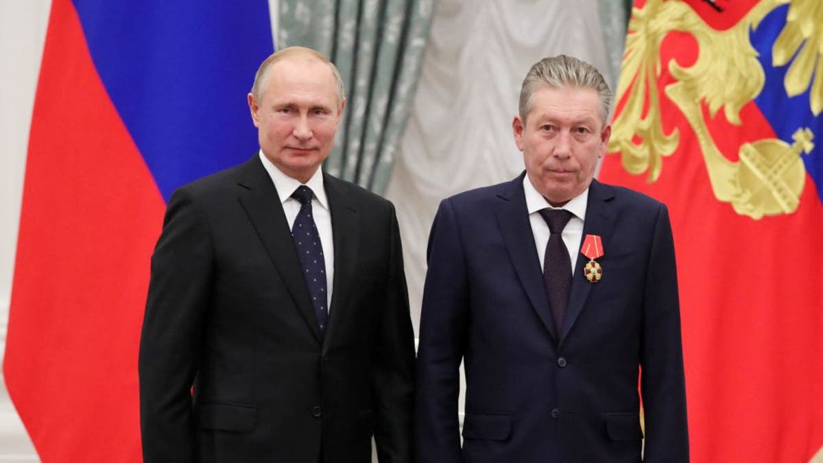 Vladimir Putin and Ravil Maganov in suits in front of a Russian flag