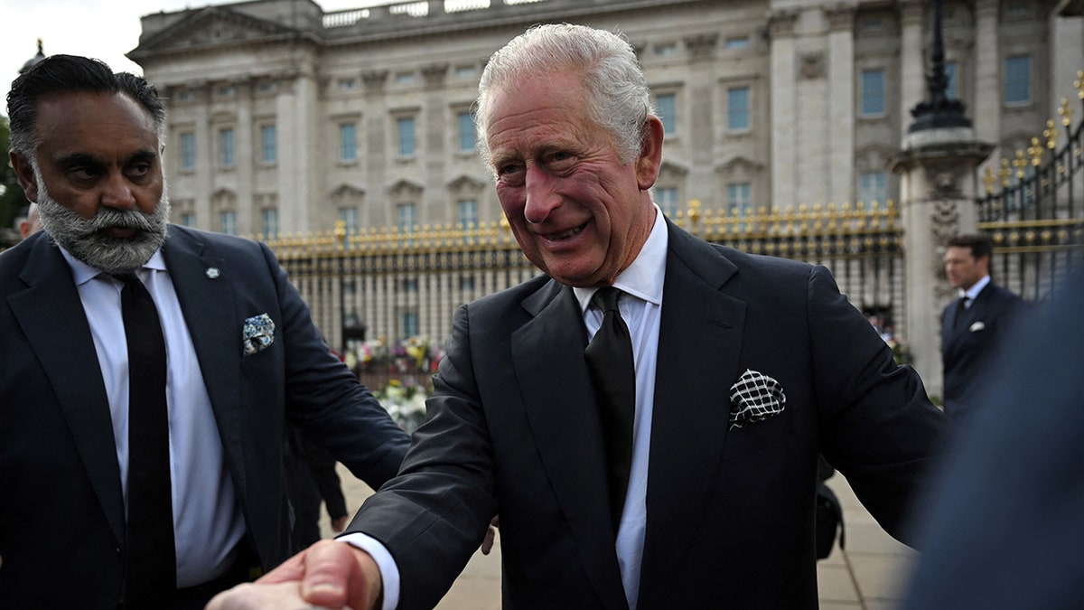 King Charles III shakes hands