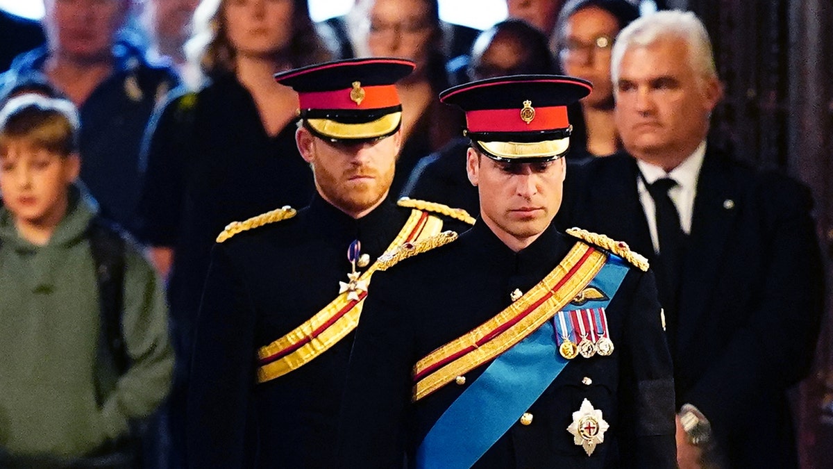Prince Harry in his military uniform stands behind brother Prince William at the Queen's vigil