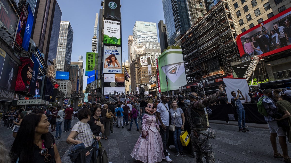 people posing for pictures and walking through times square