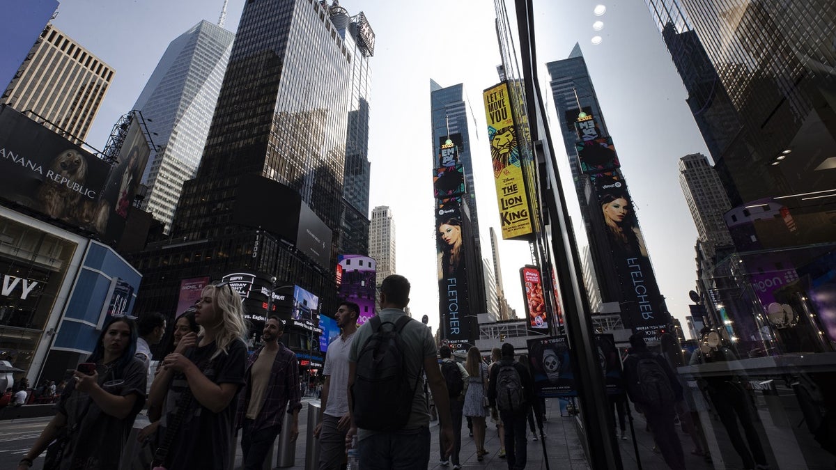 crowds of people walking along the sidewalk in times square